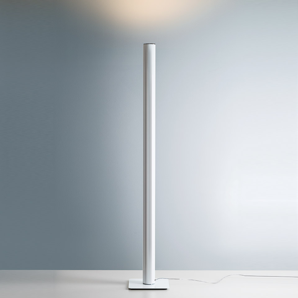 Lampada da terra Artemide Ilio: sottile colonna cilindrica bianca su base quadrata, con luce indiretta calda verso l'alto