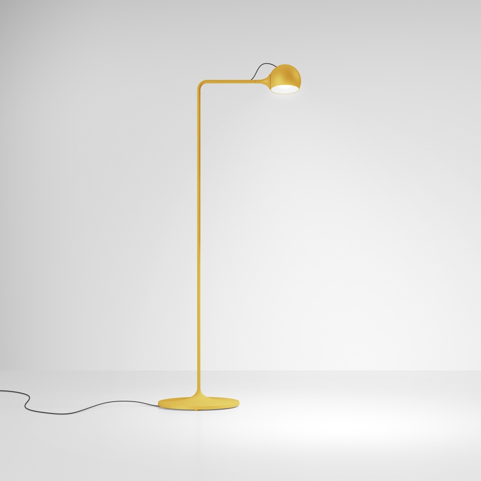 Lampada da terra Artemide Ixa gialla, con fusto sottile curvo, testa rotonda orientabile e base circolare piatta con cavo nero