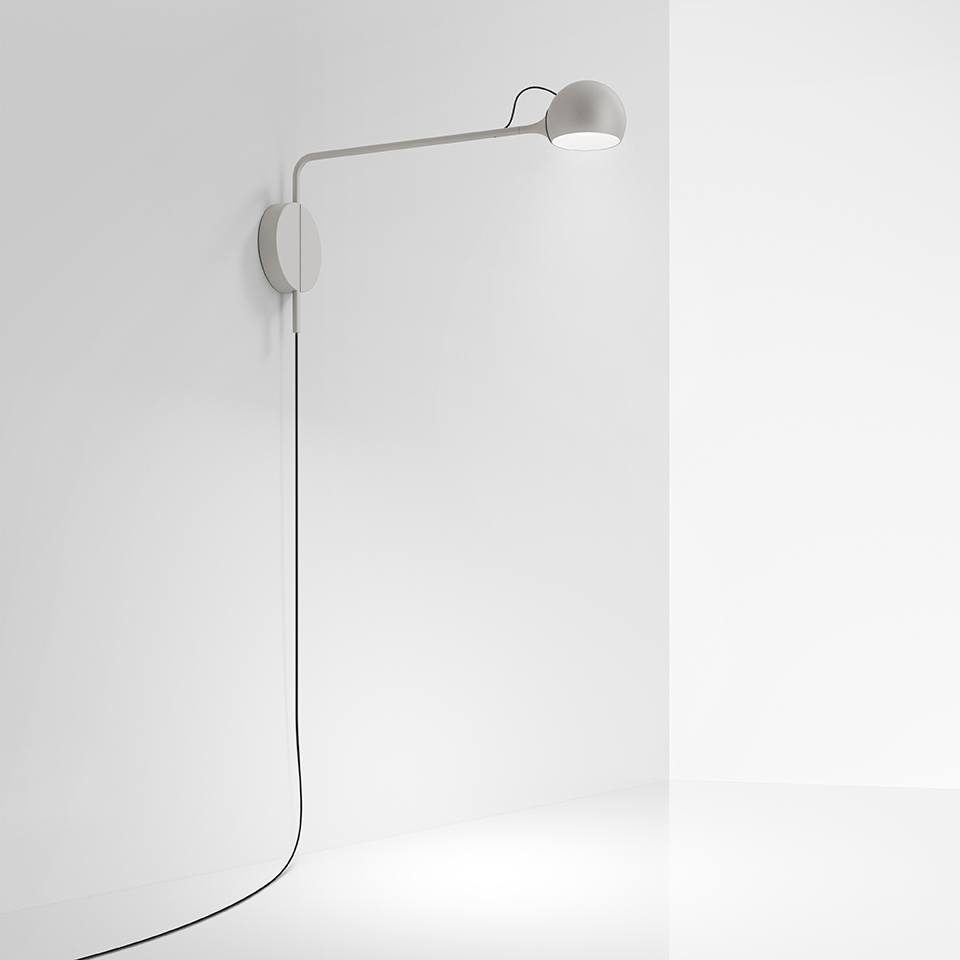 Lampada da parete Artemide Ixa bianca, con lungo braccio orizzontale, testa sferica orientabile e cavo nero su parete bianca