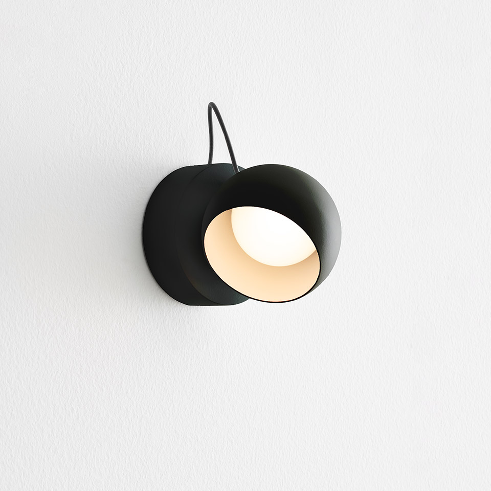 Applique Artemide Ixa in nero opaco con paralume sferico orientabile che rivela una luce interna bianco caldo