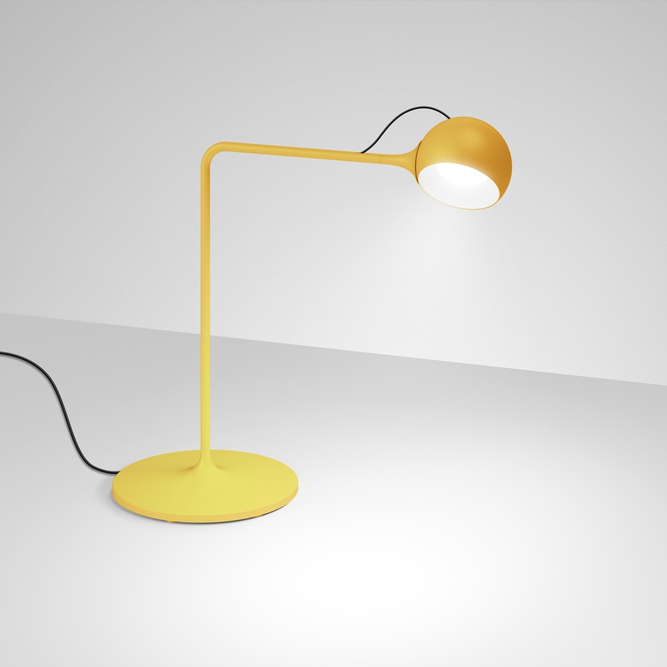 Lampada da tavolo Artemide Ixa gialla con base rotonda, braccio angolato e testa sferica orientabile che emette luce bianca calda