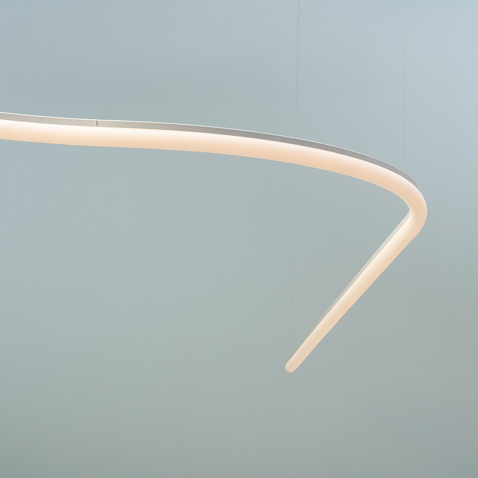 Lampada a sospensione Artemide La Linea: primo piano di un profilo LED bianco curvato che forma un anello ellittico con estremità affusolate