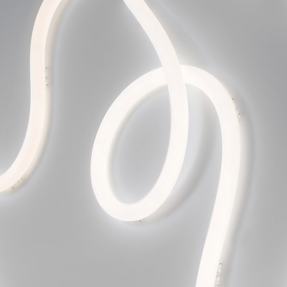 Artemide La Linea 25: tubo LED flessibile luminoso che forma eleganti curve e spirali su sfondo grigio chiaro