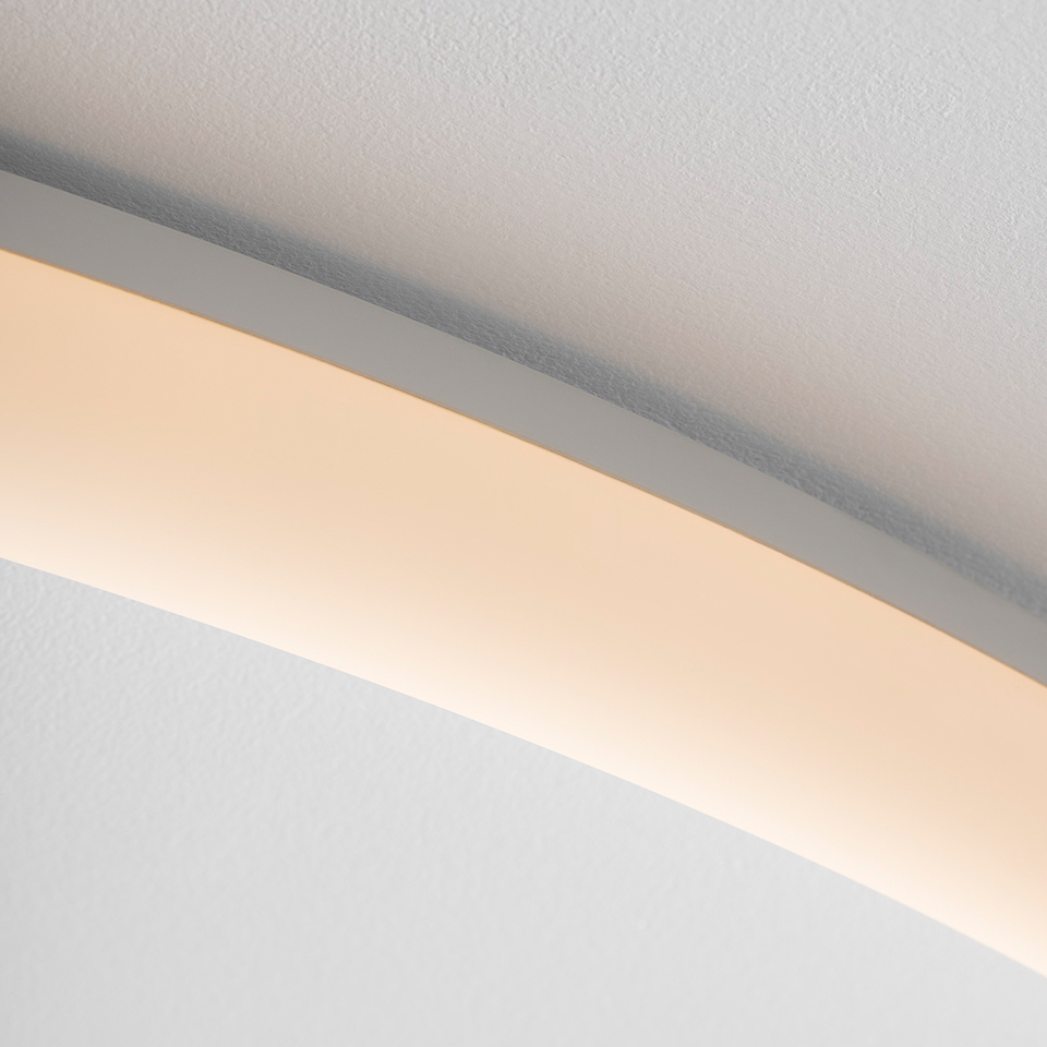Primo piano della striscia LED curva Artemide La Linea installata vicino al soffitto, che emette luce bianca calda diffusa