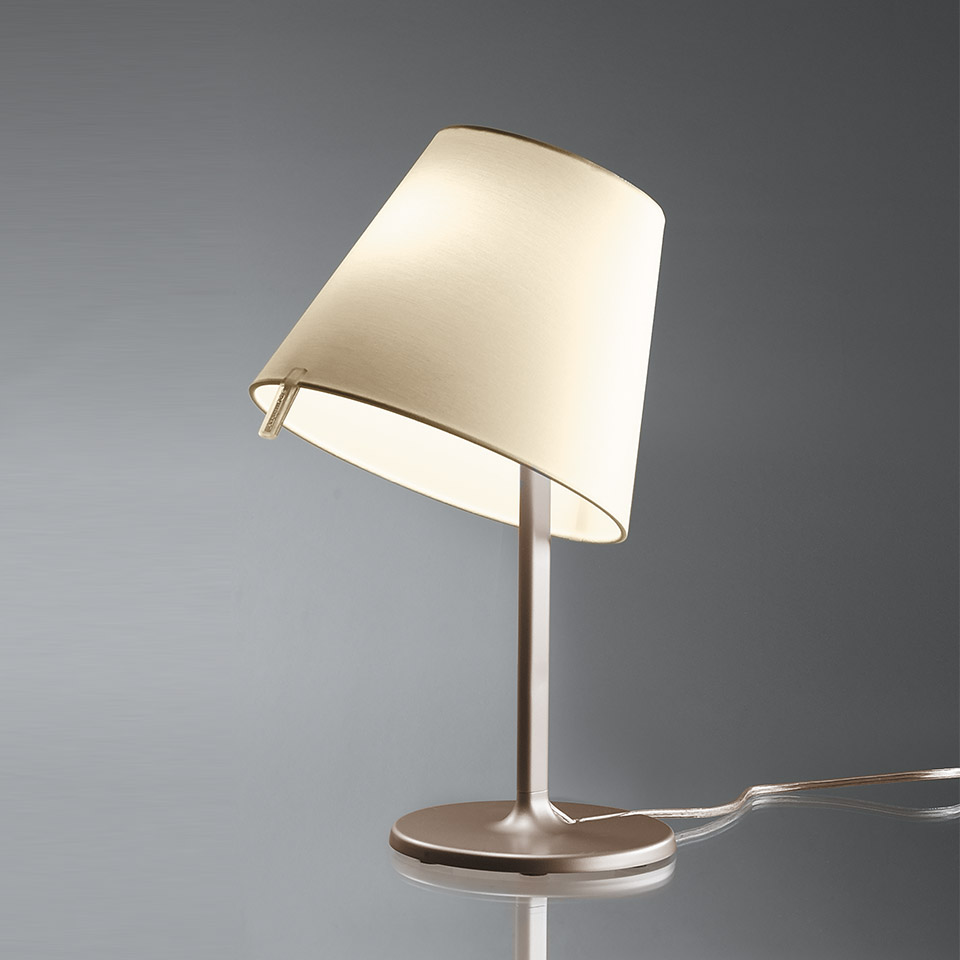 Lampada da tavolo Artemide Melampo Tavolo con paralume inclinato in tessuto color crema su sottile stelo e base in alluminio spazzolato, dolcemente illuminata