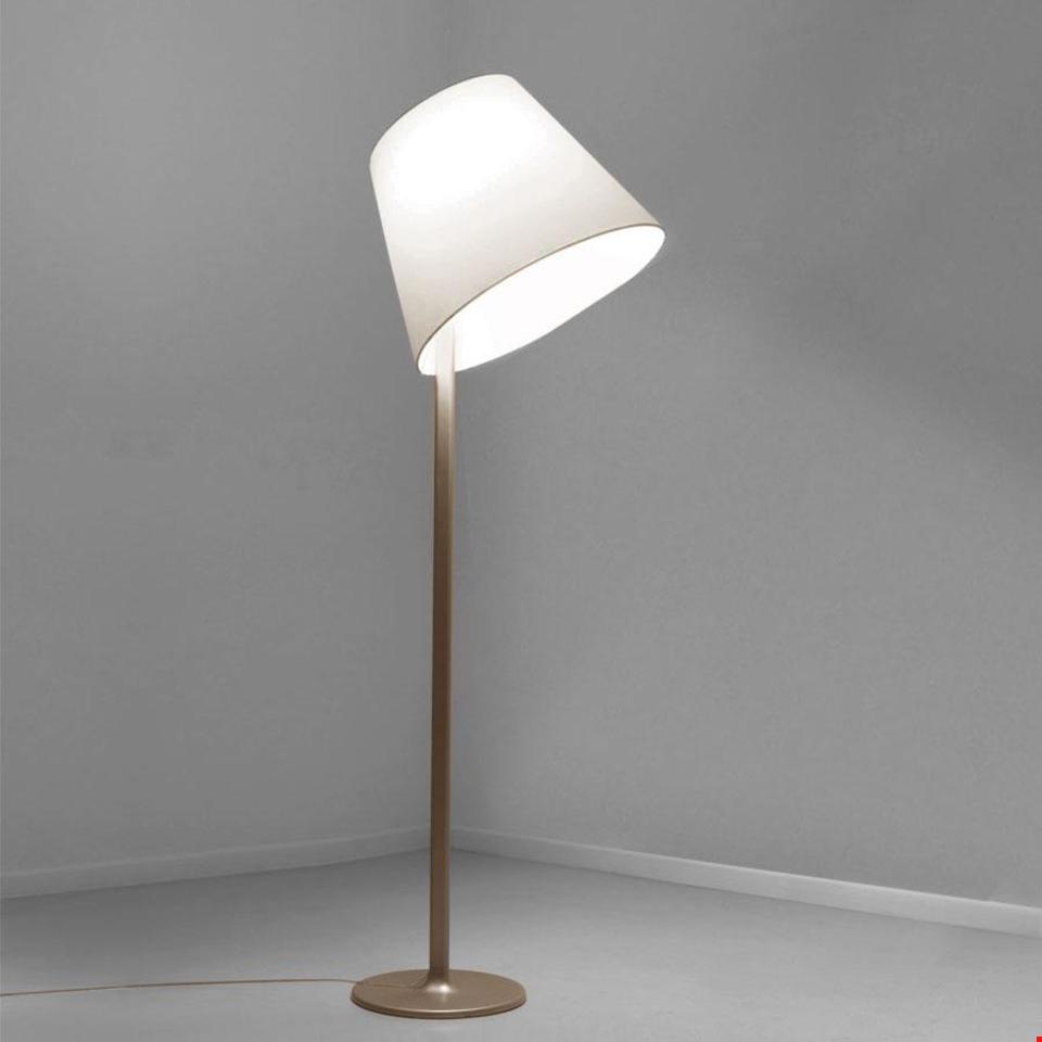 Lampada da terra Artemide Melampo Terra con paralume conico in tessuto bianco e sottile stelo in metallo oro satinato su base rotonda