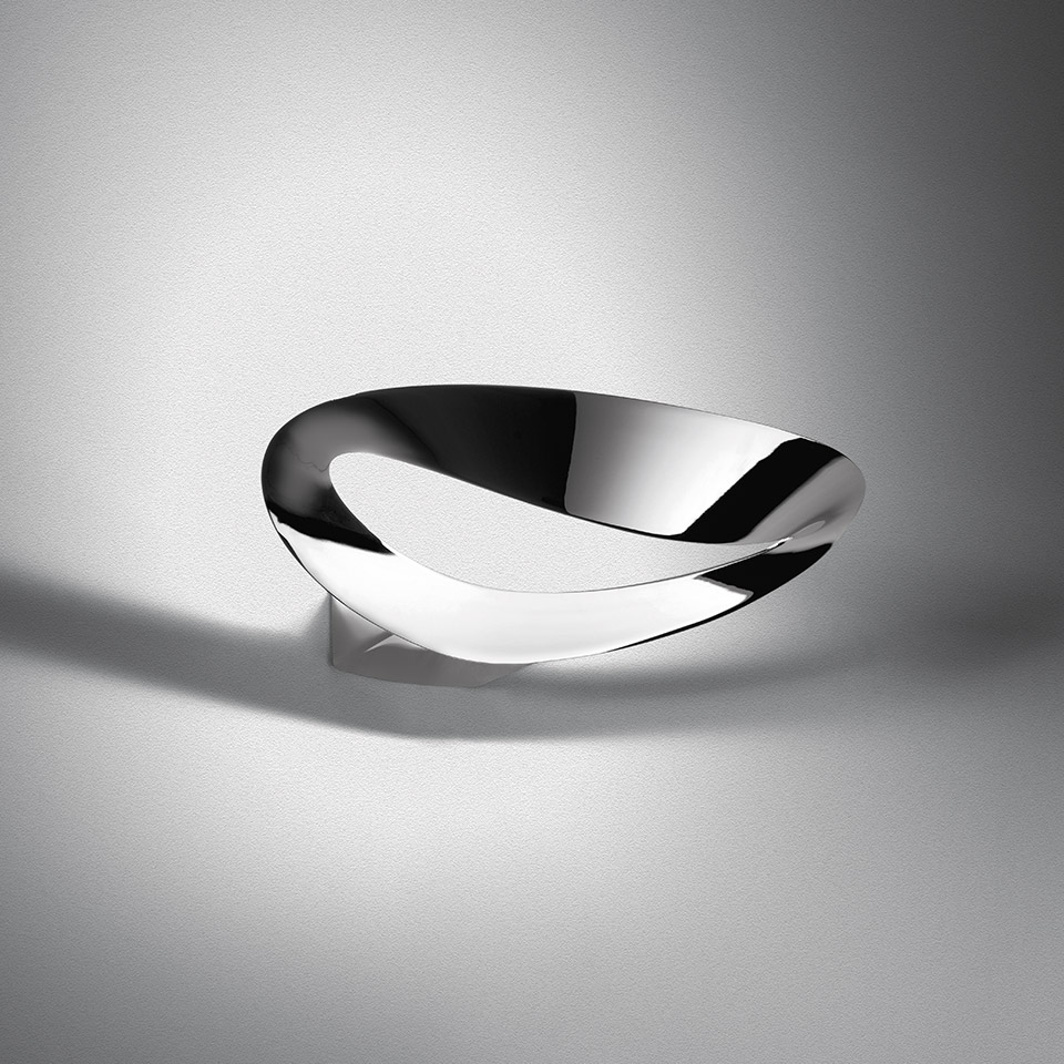 Lampada da parete Artemide Mesmeri con riflettore cromato ritorto che diffonde luce soffusa verso l'alto e il basso su parete bianca