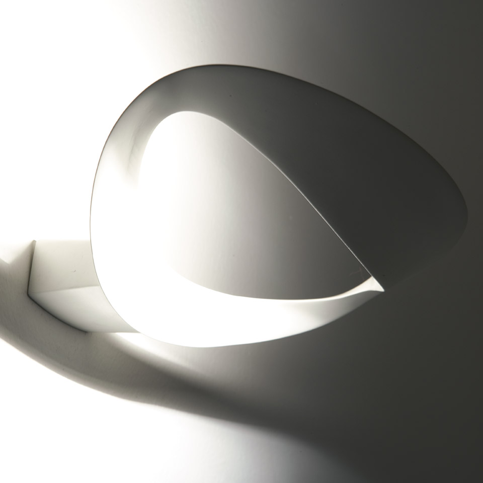 Lampada da parete Artemide Mesmeri: diffusore bianco curvato scultoreo che proietta luci e ombre suggestive sulla parete