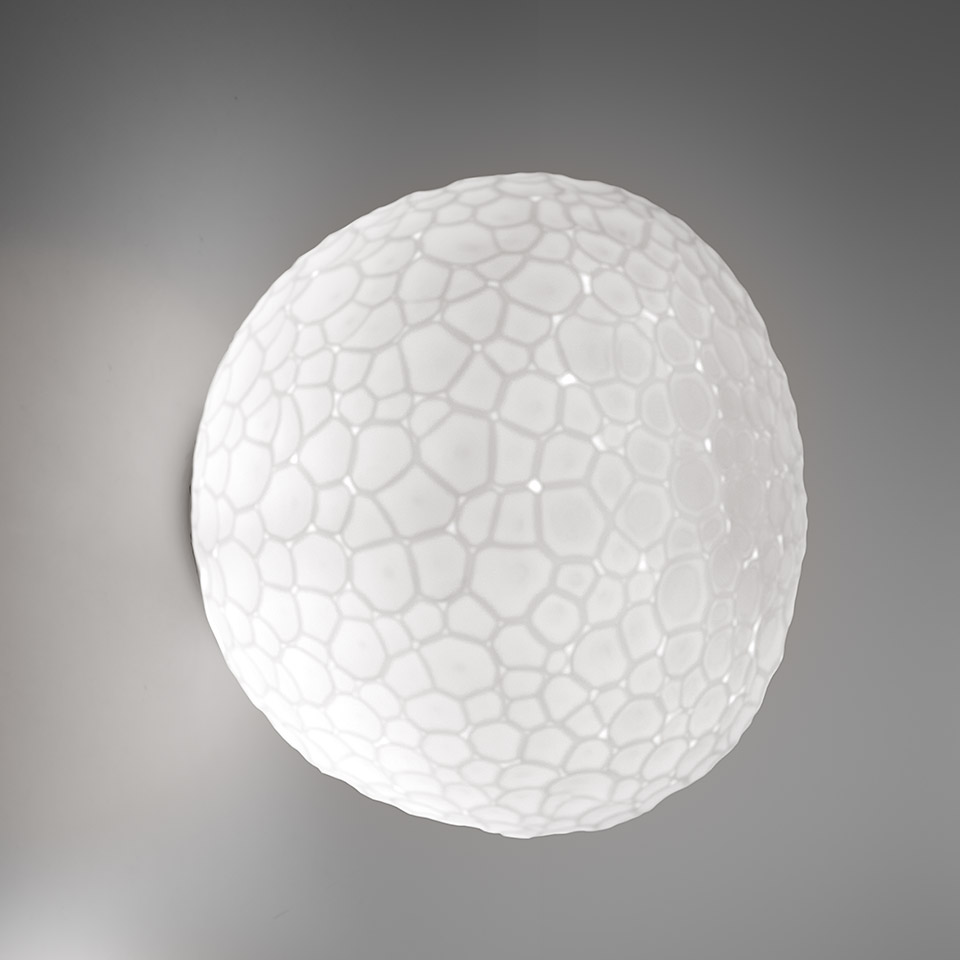 Lampada da parete/soffitto Artemide Meteorite: diffusore sferico bianco con texture cellulare organica, emette luce diffusa morbida