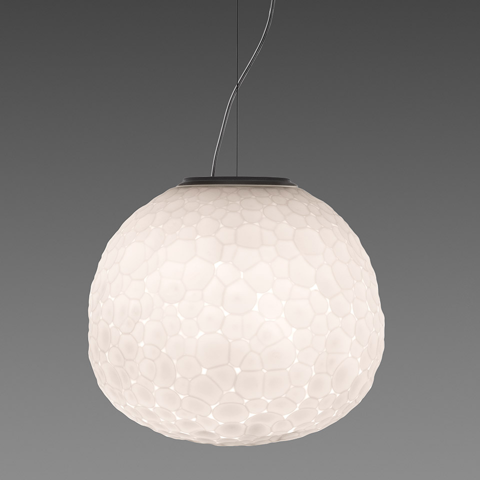 Lampada a sospensione Artemide Meteorite: grande diffusore sferico bianco con superficie a texture organica a ciottoli, sospesa da cavo scuro