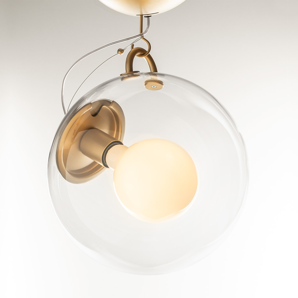 Lampada a sospensione Artemide Miconos: globo sferico in vetro trasparente con bulbo satinato interno, struttura in ottone antico e cavo di sospensione