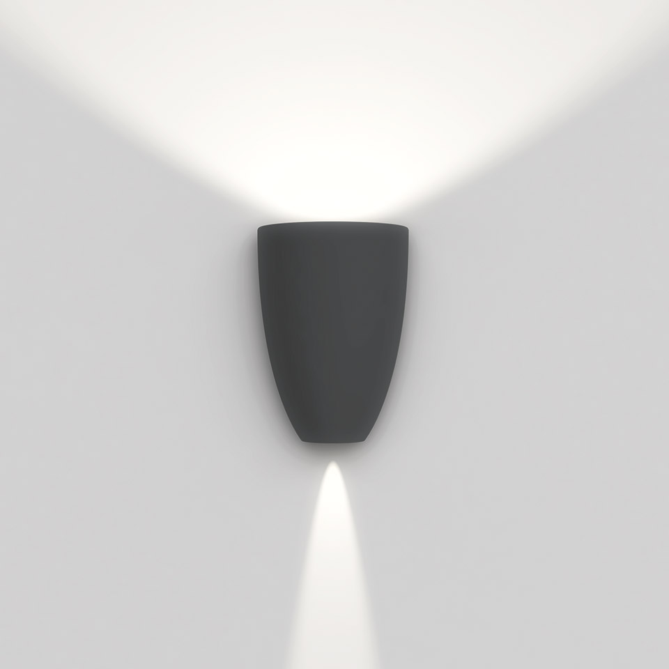 Applique Artemide Molla grigio scuro, con luce bianca diffusa verso l'alto e fascio spot verso il basso su parete bianca