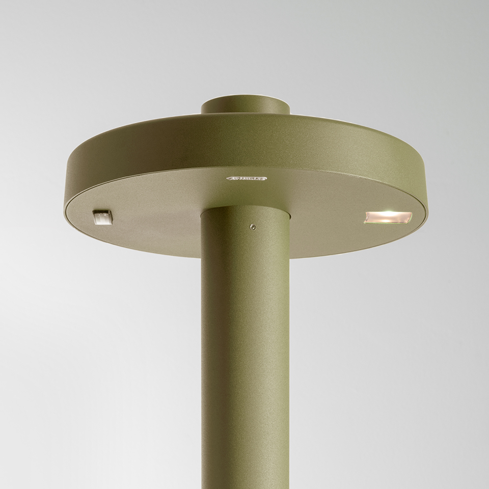 Dettaglio lampada da tavolo Artemide Needoo: fusto cilindrico verde oliva con testa a disco circolare piatta e luce LED integrata