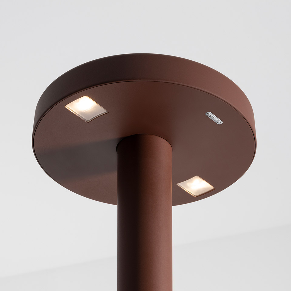 Vista dall'alto della lampada da terra Artemide Needoo: testa a disco rotonda marrone scuro con due luci LED quadrate incassate su un fusto cilindrico
