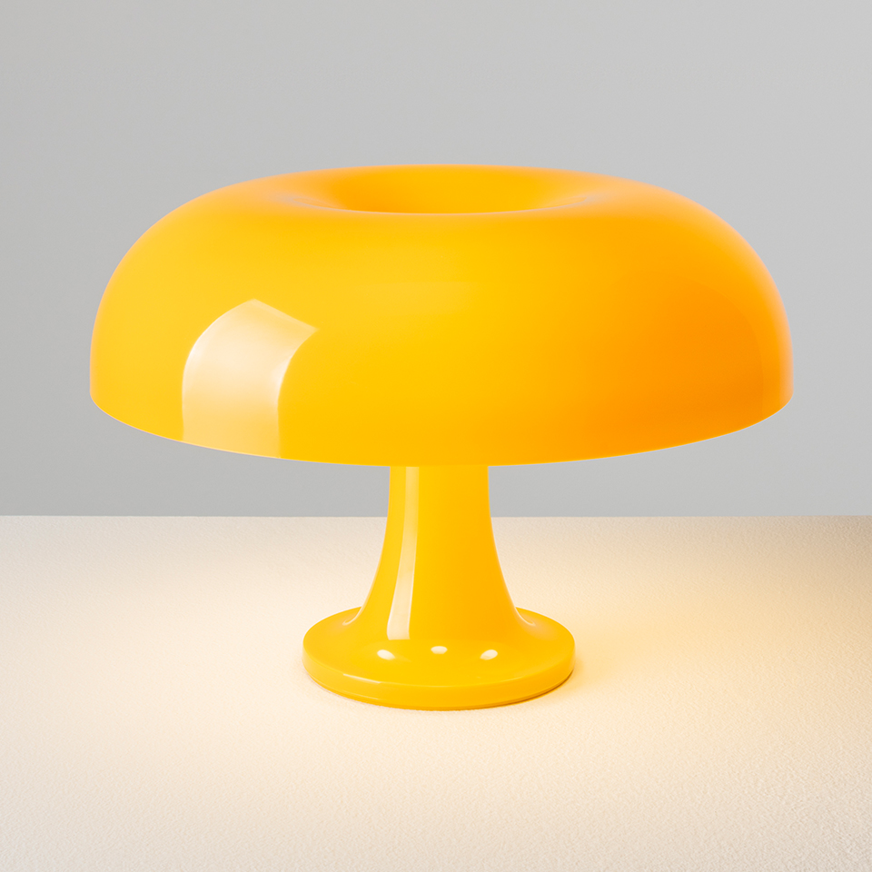 Lampada da tavolo Artemide Nessino in giallo vivace, con paralume a fungo arrotondato e base a piedistallo, con luce calda su una superficie - 2