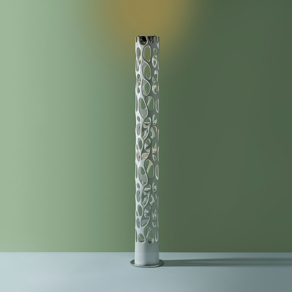 Artemide New Nature floor lamp: tall white cylindrical column with organic perforations, chrome top emitting warm upward light