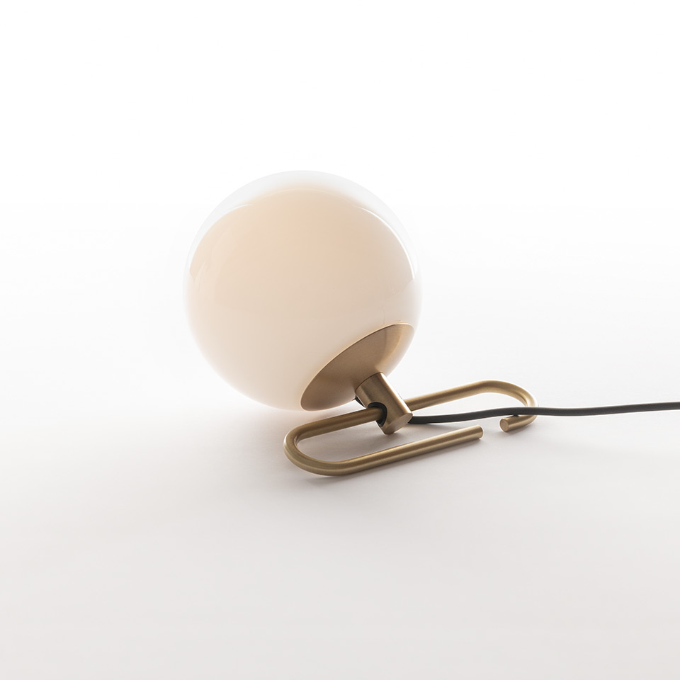 Artemide NH1217 table lamp: opal white glass sphere on brushed brass U-shaped base with black power cord