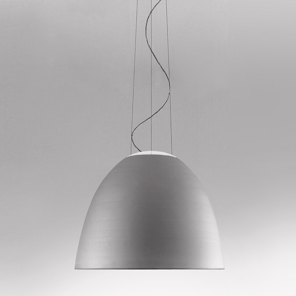 Lampada a sospensione Artemide Nur con paralume a cupola in alluminio spazzolato, sospesa da sottili cavi e un cavo ritorto su sfondo grigio