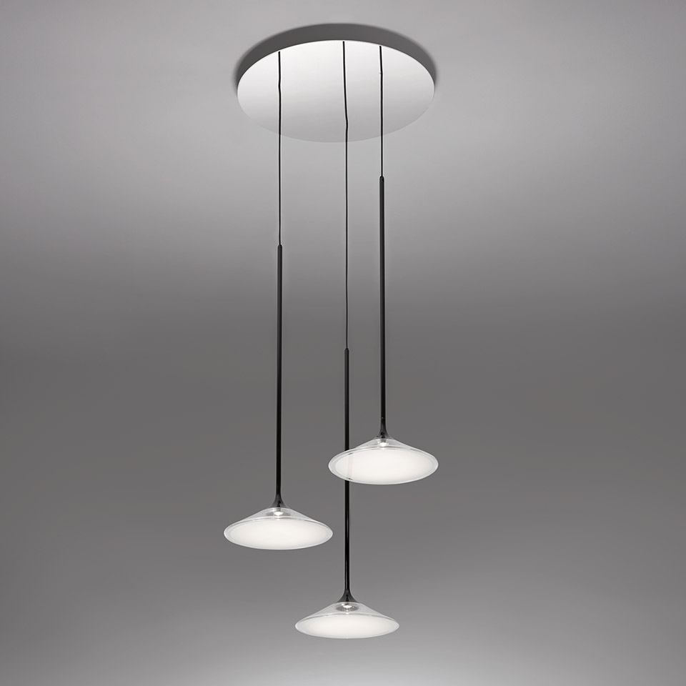 Artemide Orsa Cluster: three pendant lights with flat opal white shades on black cords, suspended from a round white ceiling canopy
