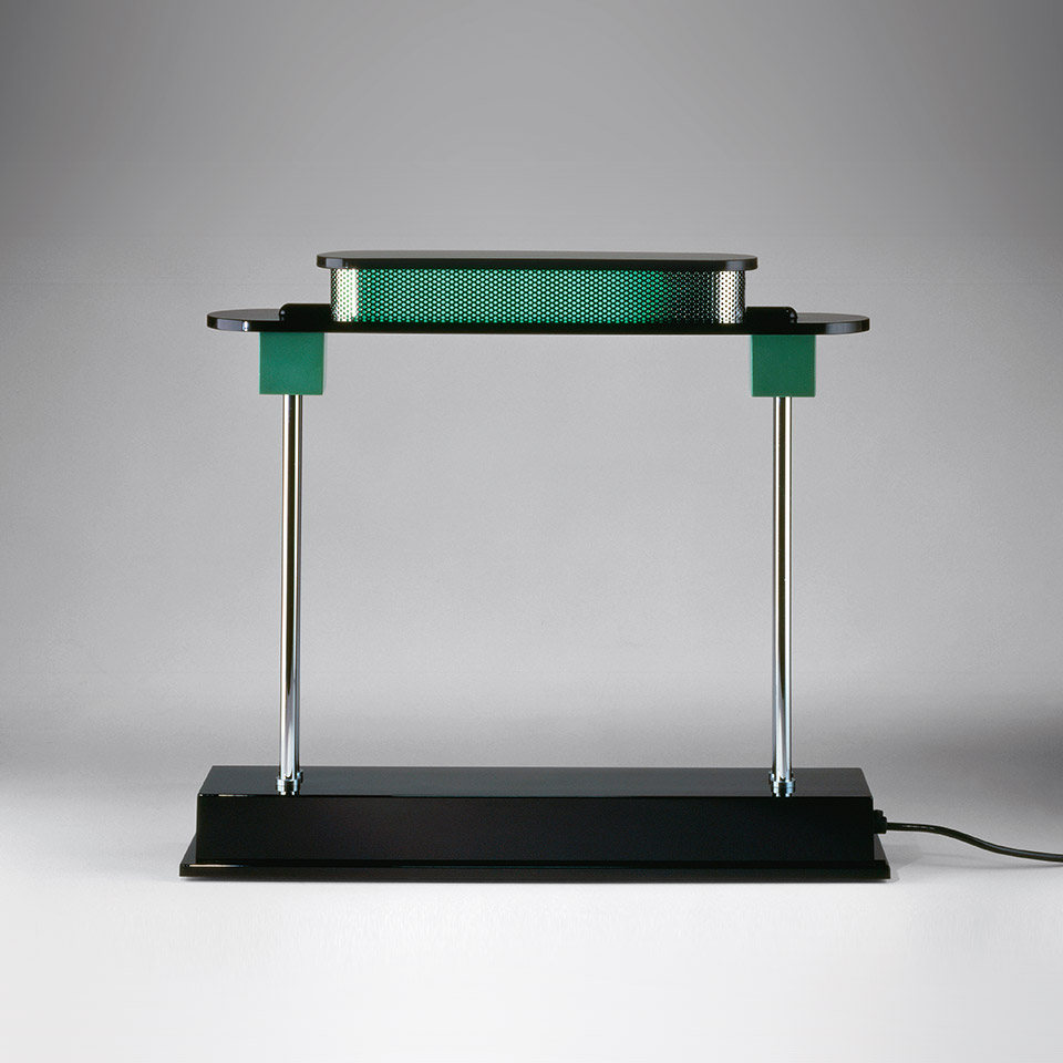 Lampada da tavolo Artemide Pausania: base rettangolare nera, aste verticali cromate, dettagli verdi, diffusore forato con luce calda