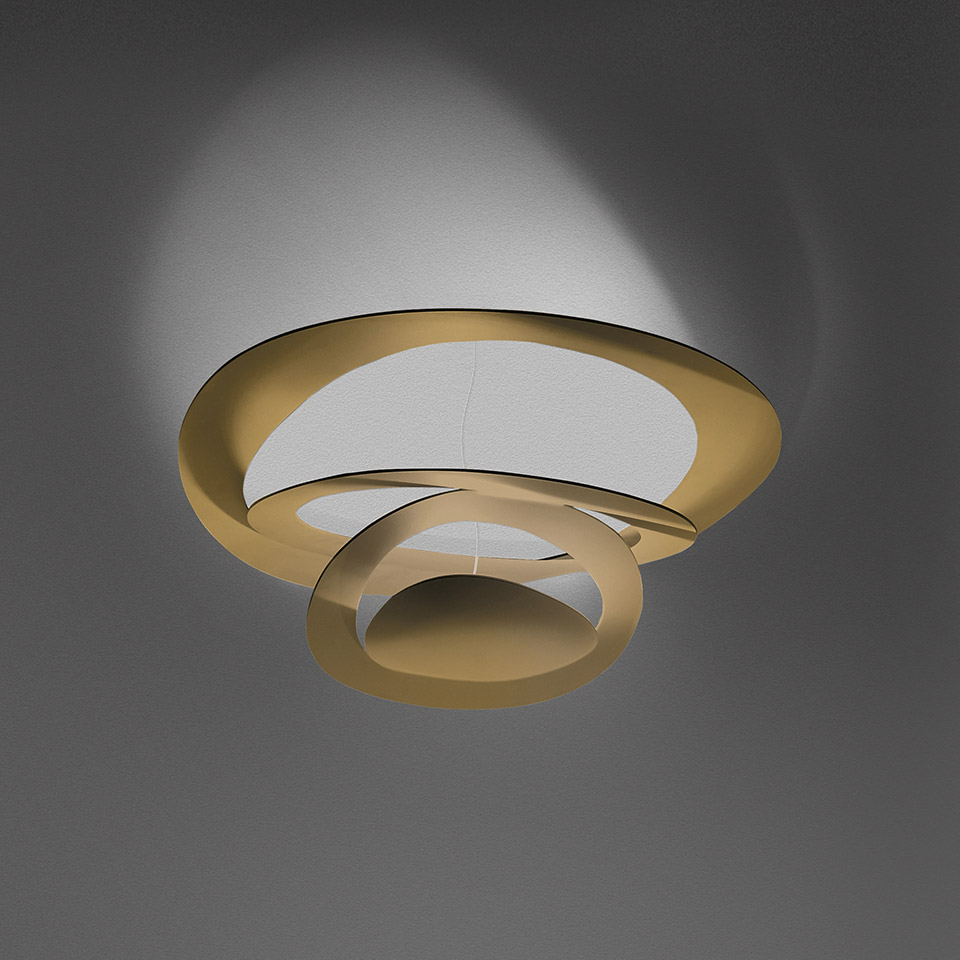 Artemide Pirce Soffitto ceiling lamp in gold finish, featuring two interlocking spiral rings that emit soft upward light.