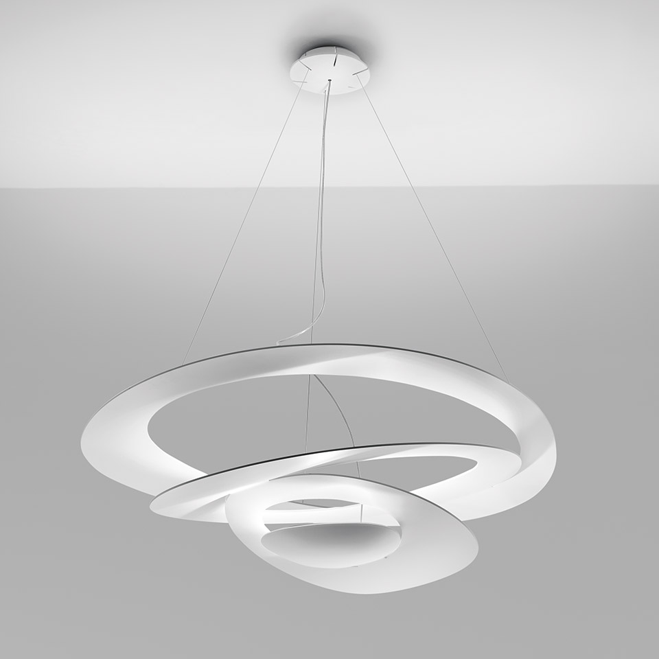 Lampada a sospensione Artemide Pirce in bianco, con forma a nastro spirale scultoreo e sorgente luminosa LED integrata, sospesa da sottili cavi.