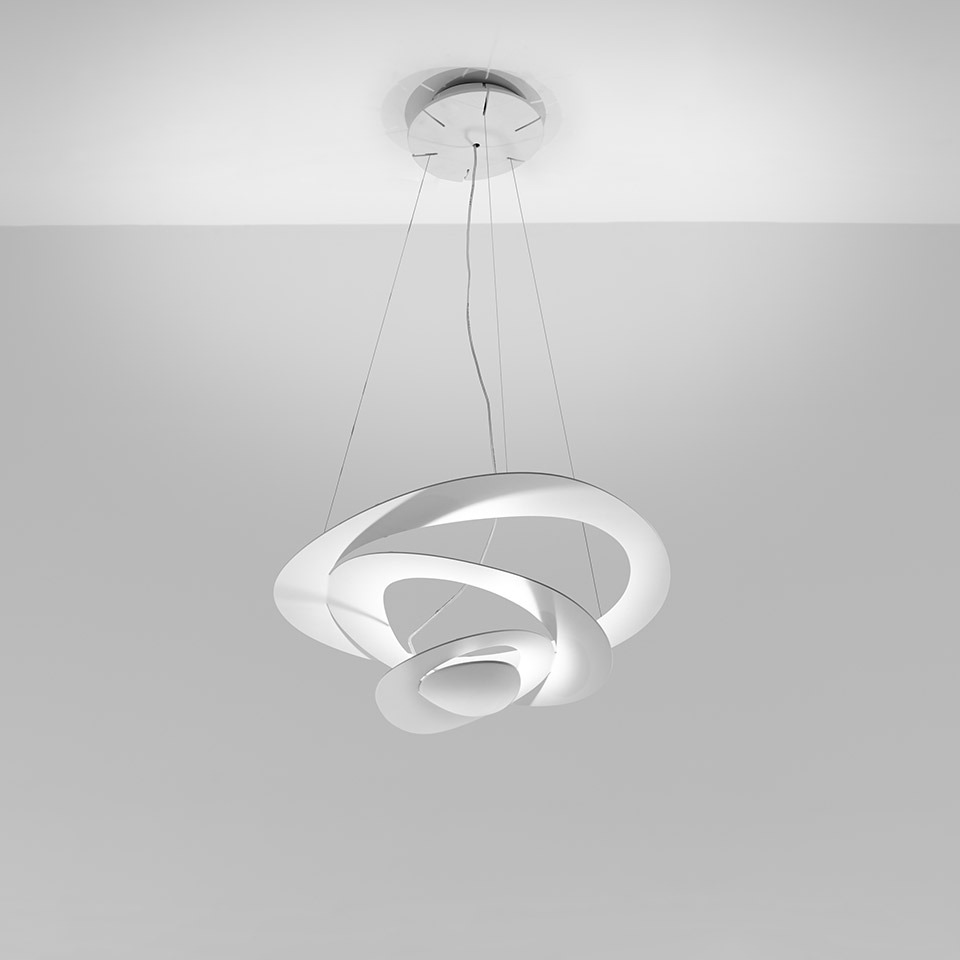 Lampada a sospensione Artemide Pirce in bianco, con anelli a spirale intrecciati che emettono luce indiretta, sospesa dal soffitto con sottili cavi