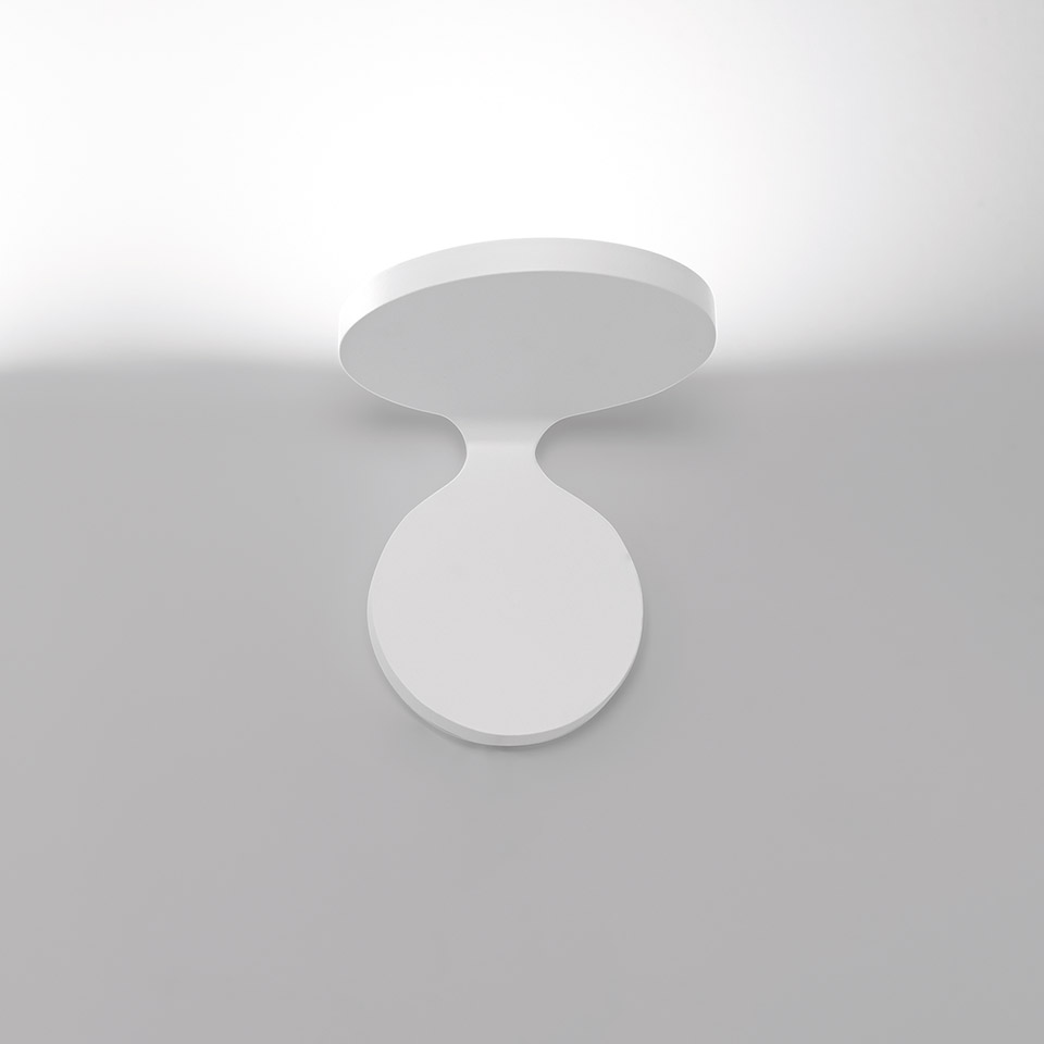 Lampada da parete/soffitto Artemide Rea in bianco, con due dischi circolari collegati da un collo curvo, che emette luce soffusa verso l'alto