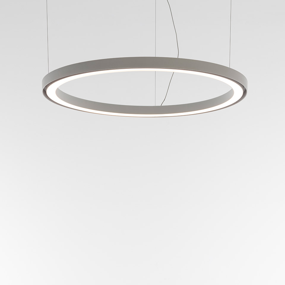 Lampada a sospensione Artemide Ripple: grande anello circolare grigio con striscia LED integrata che emette luce bianca calda, sospesa da sottili cavi