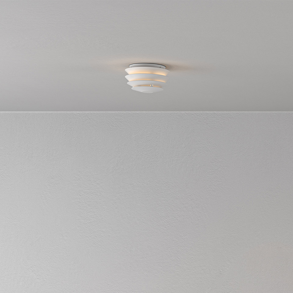 Plafoniera Artemide Slicing in bianco, con anelli diffusori orizzontali sovrapposti che emettono luce calda, installata a soffitto bianco