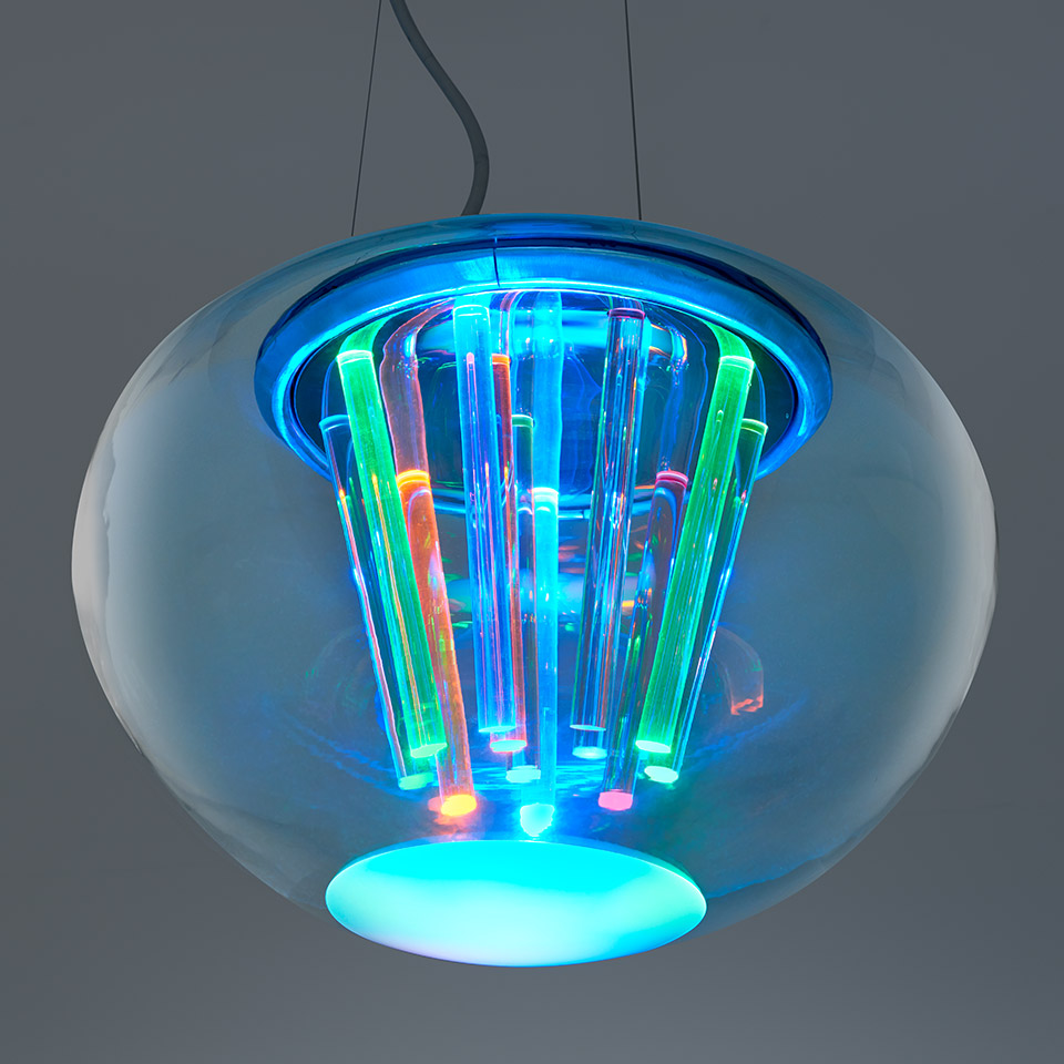Lampada a sospensione Artemide Spectral Light: globo in vetro blu trasparente con tubi LED multicolori che emettono luce vivace in ciano, verde e arancione
