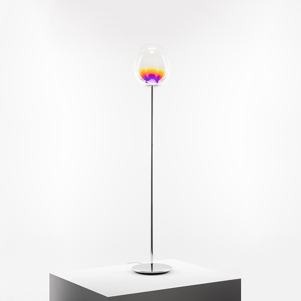 Lampada da terra Artemide Stellar Nebula: alto fusto cromato, diffusore ovale in vetro trasparente con luce a gradiente giallo, arancione e viola