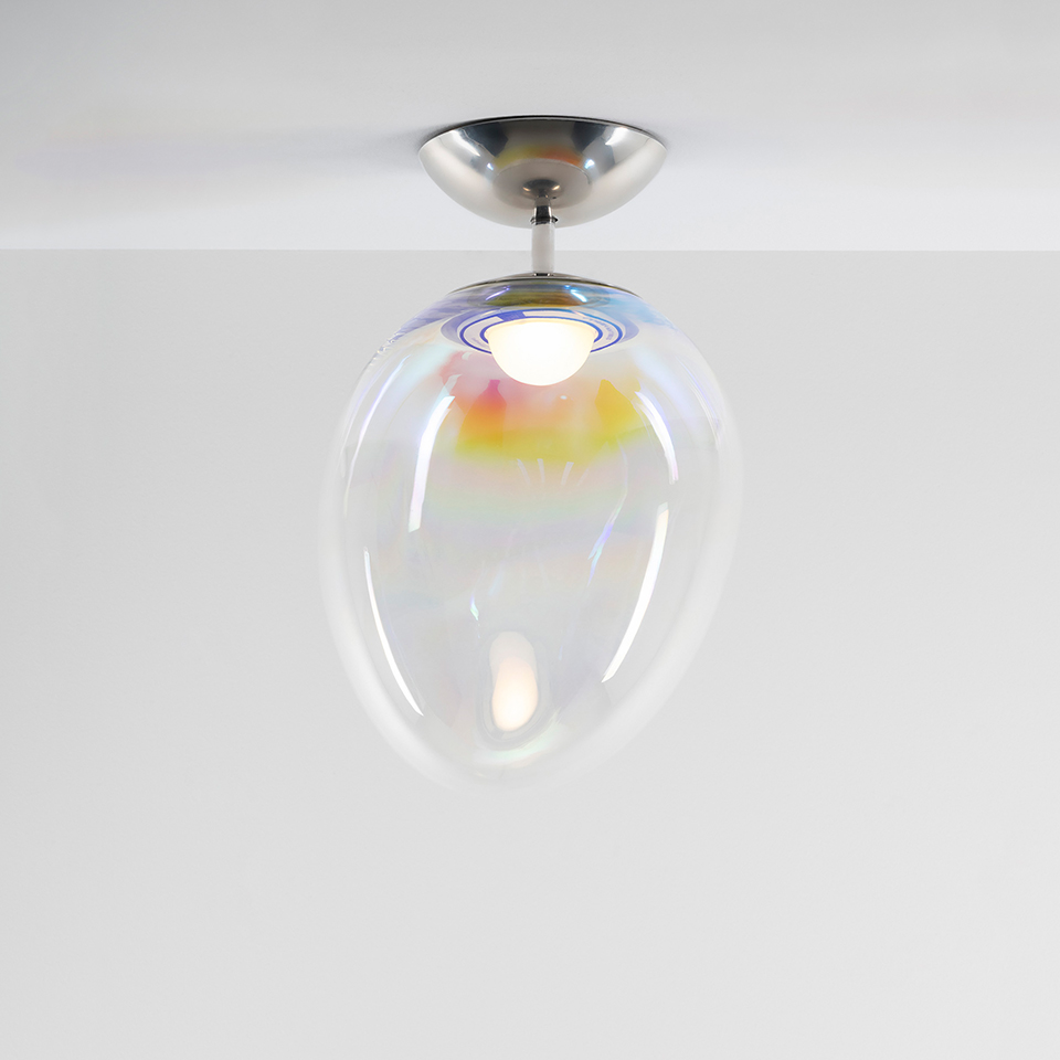 Lampada da soffitto Artemide Stellar Nebula con diffusore in vetro ovale iridescente che riflette tonalità arcobaleno, montata su rosone in nichel spazzolato
