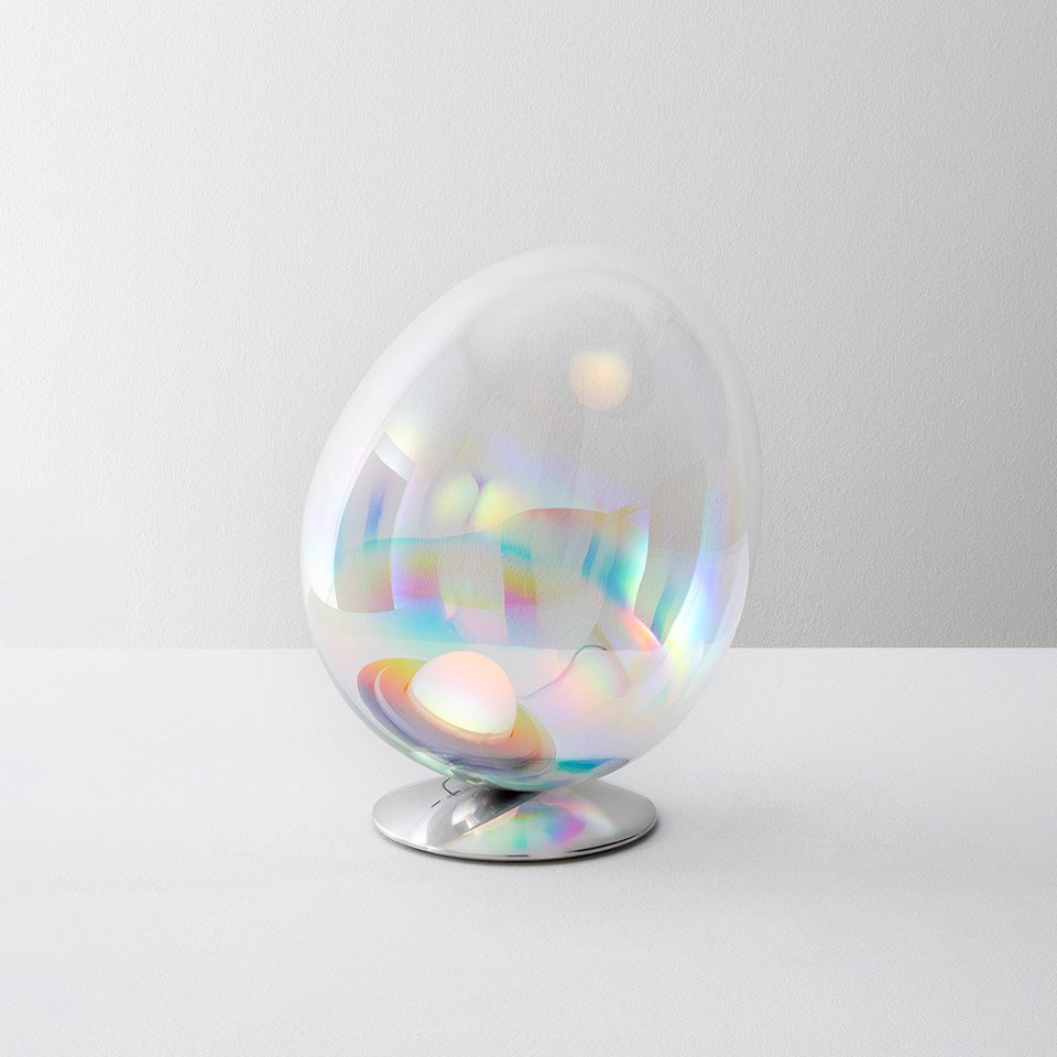 Lampada da tavolo Artemide Stellar Nebula: diffusore in vetro iridescente a forma di uovo con riflessi arcobaleno su base cromata lucida
