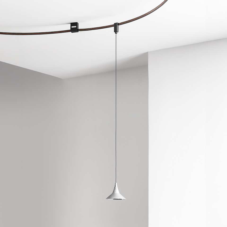 Lampada a sospensione Artemide Sylt con paralume conico bianco appesa a un cavo sottile su binario a soffitto scuro