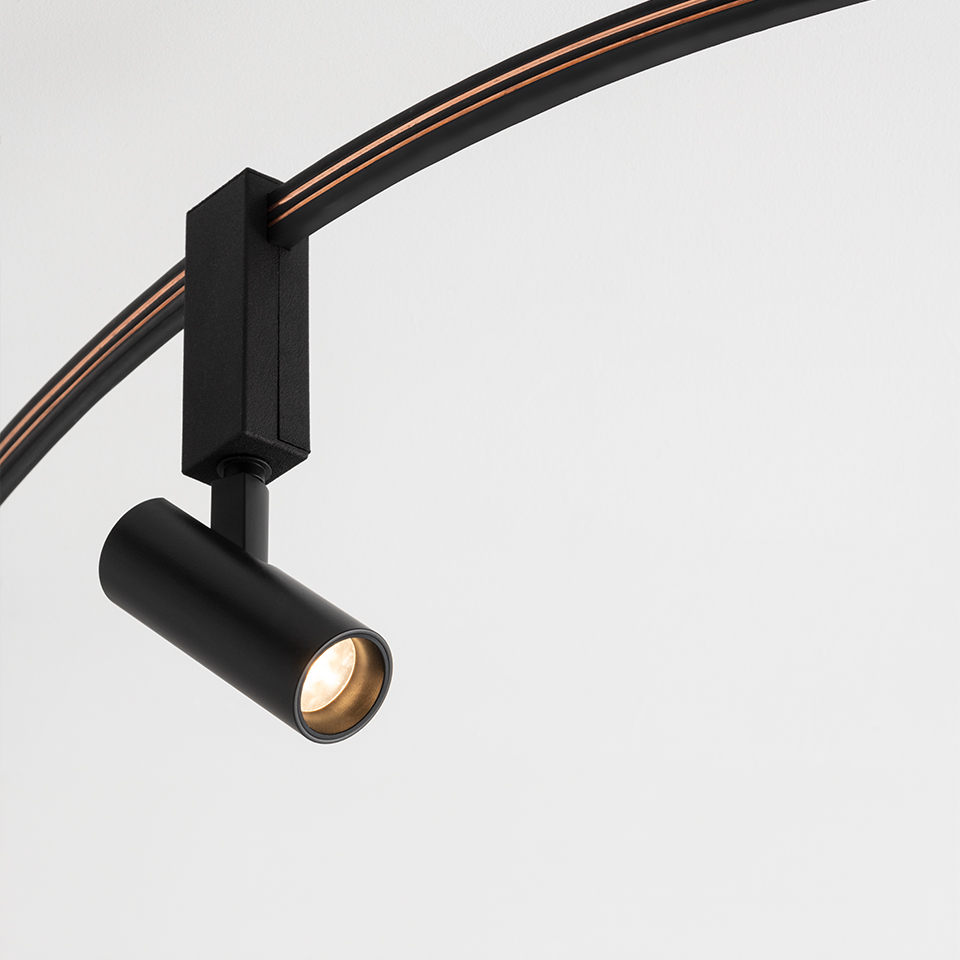 Faretto su binario Artemide Sylt nero opaco, testa cilindrica con LED caldo, montato su binario curvo nero e rame