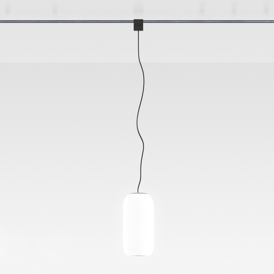 Lampada a sospensione Artemide Sylt: diffusore ovale in vetro opalino bianco sospeso da cavo nero a una rosetta da binario scura a soffitto
