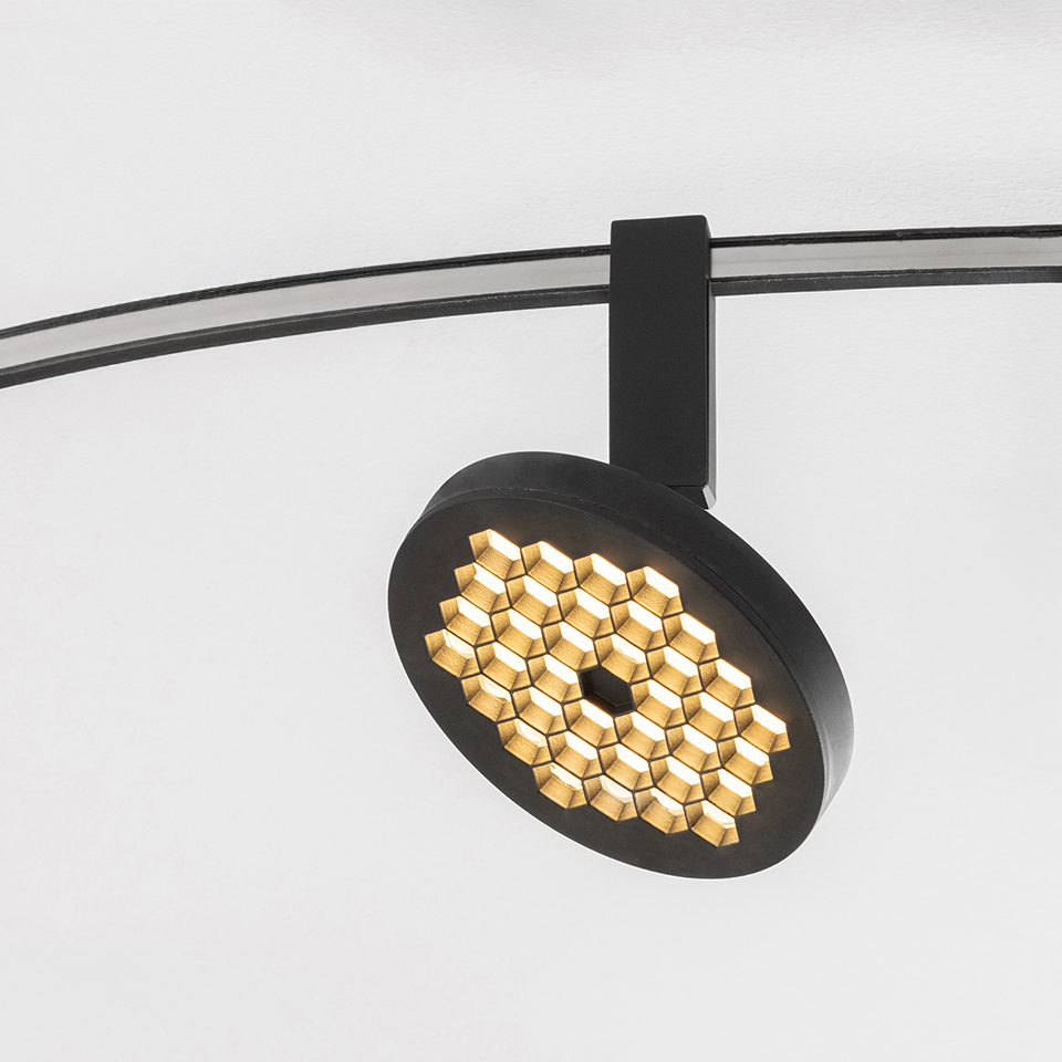 Faretto su binario Artemide Sylt nero opaco con testa circolare a griglia LED a nido d'ape, montato su binario curvo a soffitto