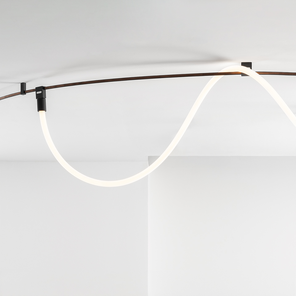 Lampada da soffitto Artemide Sylt: tubo LED bianco luminoso flessibile a forma di onda, montato sul soffitto con staffe in metallo scuro