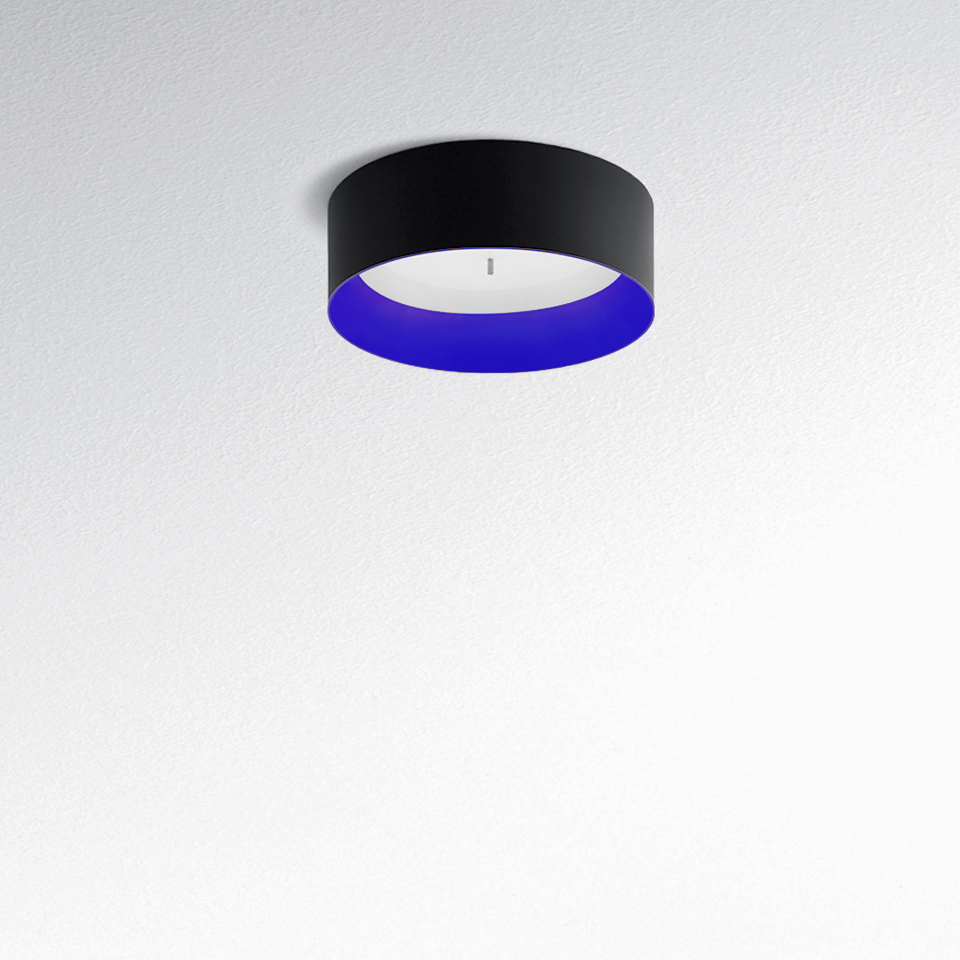 Plafoniera Tagora Soffitto 570 di Artemide: esterno cilindrico nero, diffusore interno blu vibrante, montata a filo su soffitto bianco