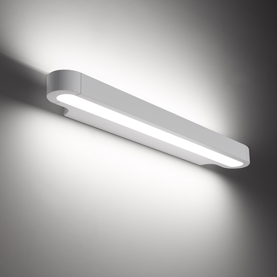 Artemide Talo wall lamp: sleek horizontal LED bar in white/grey finish, emitting warm upward and downward light against a grey wall
