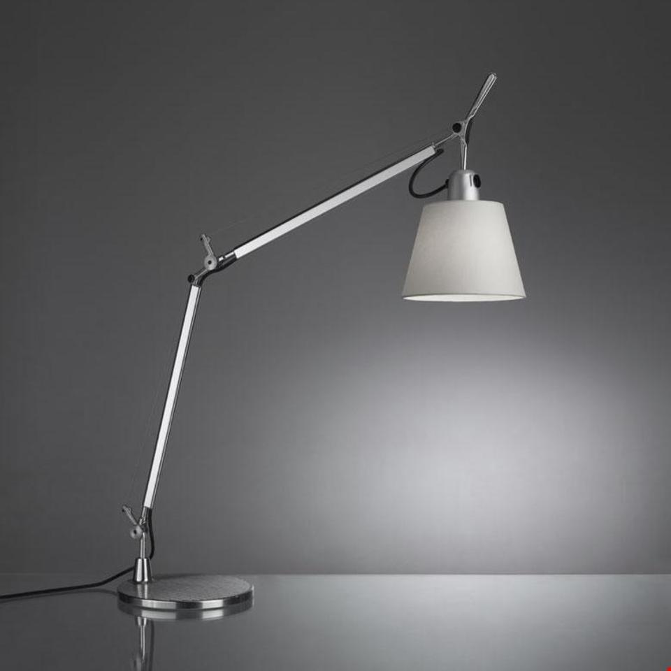 Artemide Tolomeo Basculante table lamp with adjustable aluminum arm, conical white shade, and circular base on reflective surface