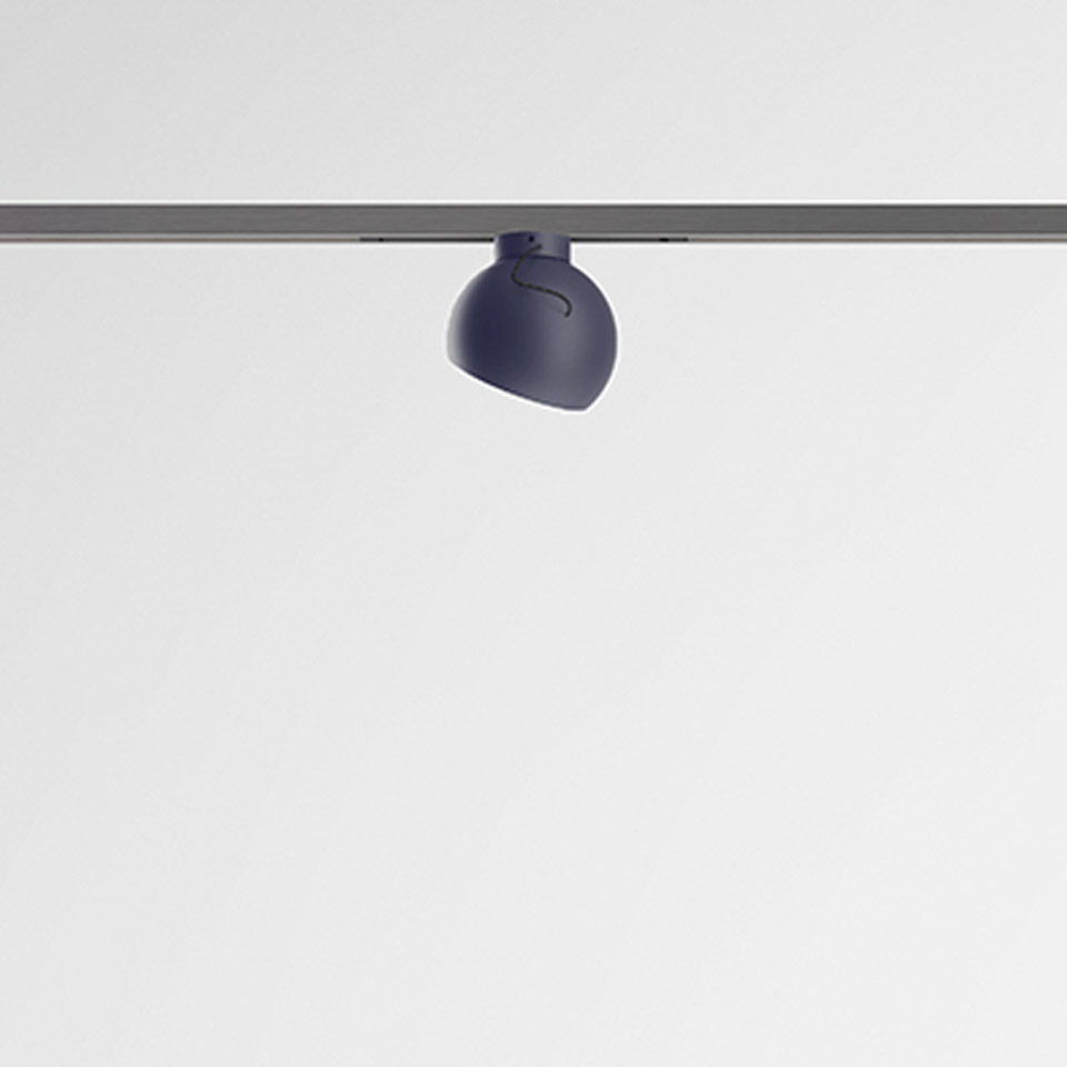 Artemide Turn Around System: faretto arrotondato blu scuro montato su binario a soffitto grigio, testa direzionale orientabile