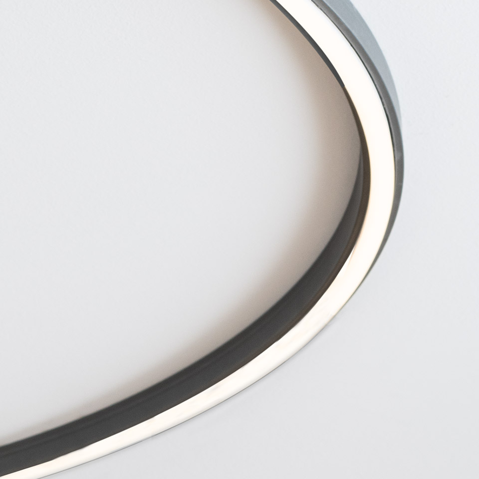 Primo piano del sistema Artemide Turn Around: anello LED circolare con cornice in metallo scuro che emette luce bianca calda su sfondo bianco