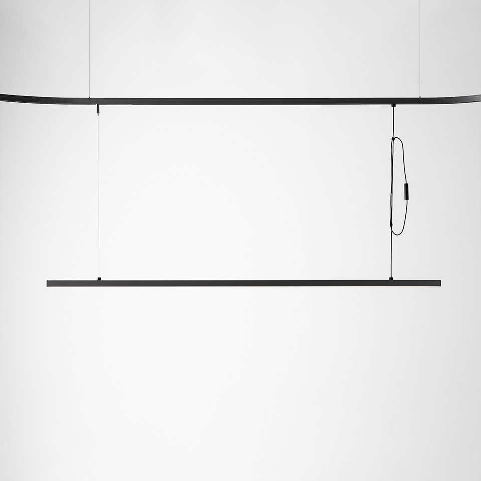 Artemide Turn Around System: sottile lampada a sospensione LED lineare nera, appesa con cavi sottili a una guida curva a soffitto con gestione cavi