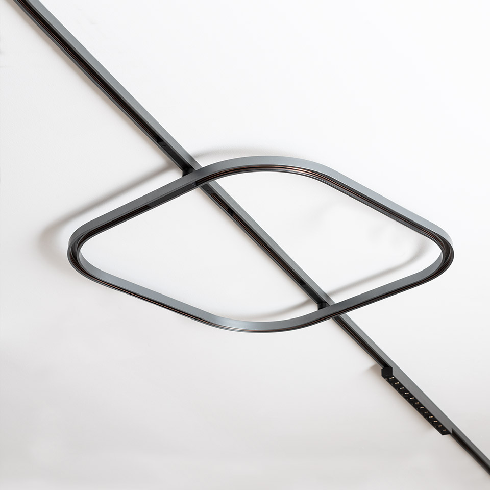 Artemide Turn Around System: anello LED in metallo scuro con curva a forma di occhio montato su binario a soffitto, design minimalista