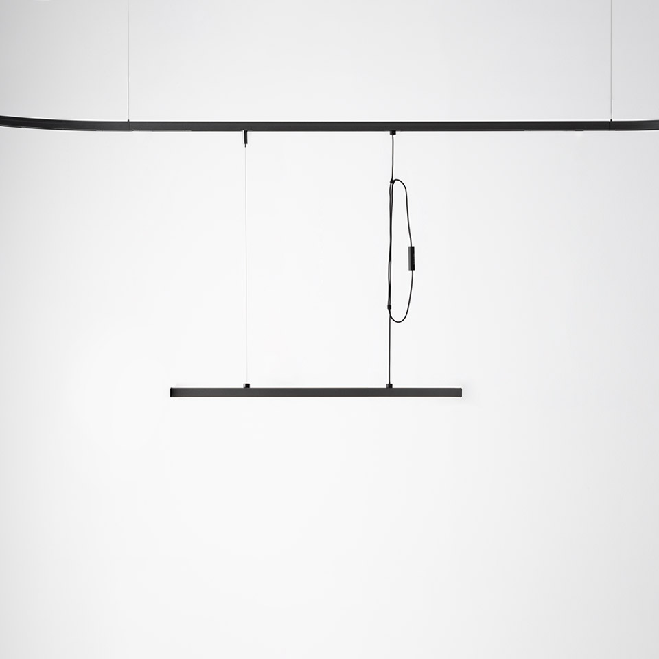 Artemide Turn Around System: sottile lampada a sospensione lineare nera appesa a binario a soffitto tramite cavi sottili e cavo ad anello