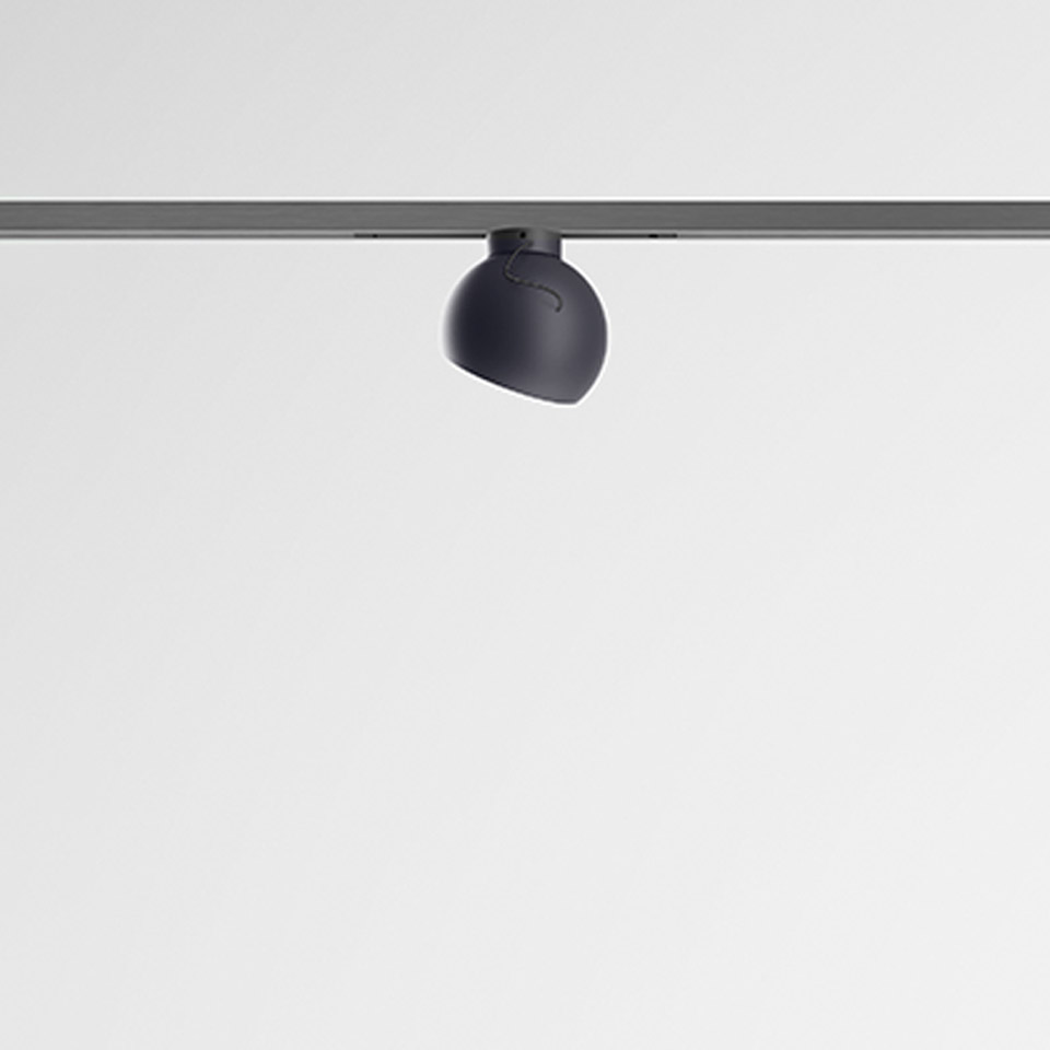 Artemide Turn Around System: faretto orientabile grigio scuro con testa arrotondata montato su binario a soffitto
