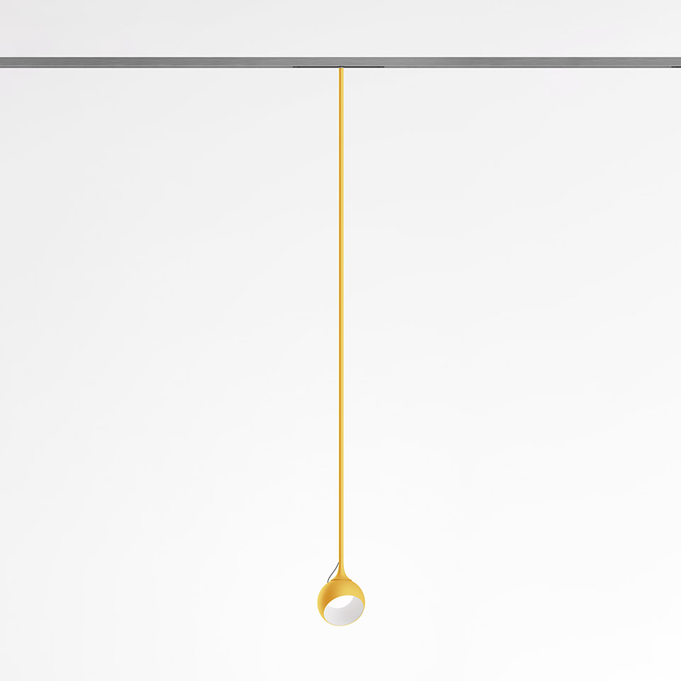 Artemide Turn Around System: lampada a sospensione gialla con stelo sottile e piccola testa sferica inclinabile, montata su binario a soffitto