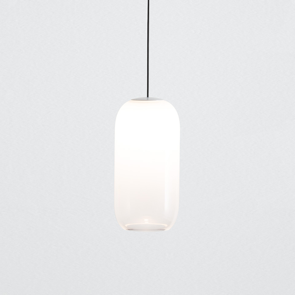 Lampada a sospensione Artemide Turn Around con diffusore in vetro opalino bianco ovale allungato, sospesa da un cavo nero